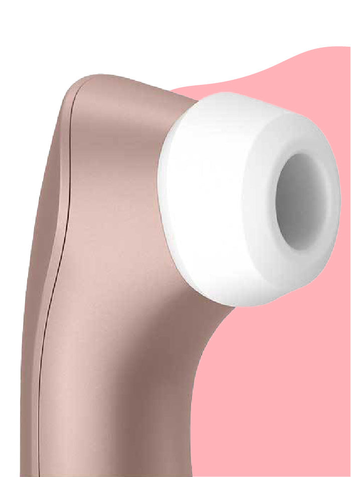 A close up view of the Satisfyer PRO 2+ clitoris stimulator's silicone head in front of a light pink and white curvy background